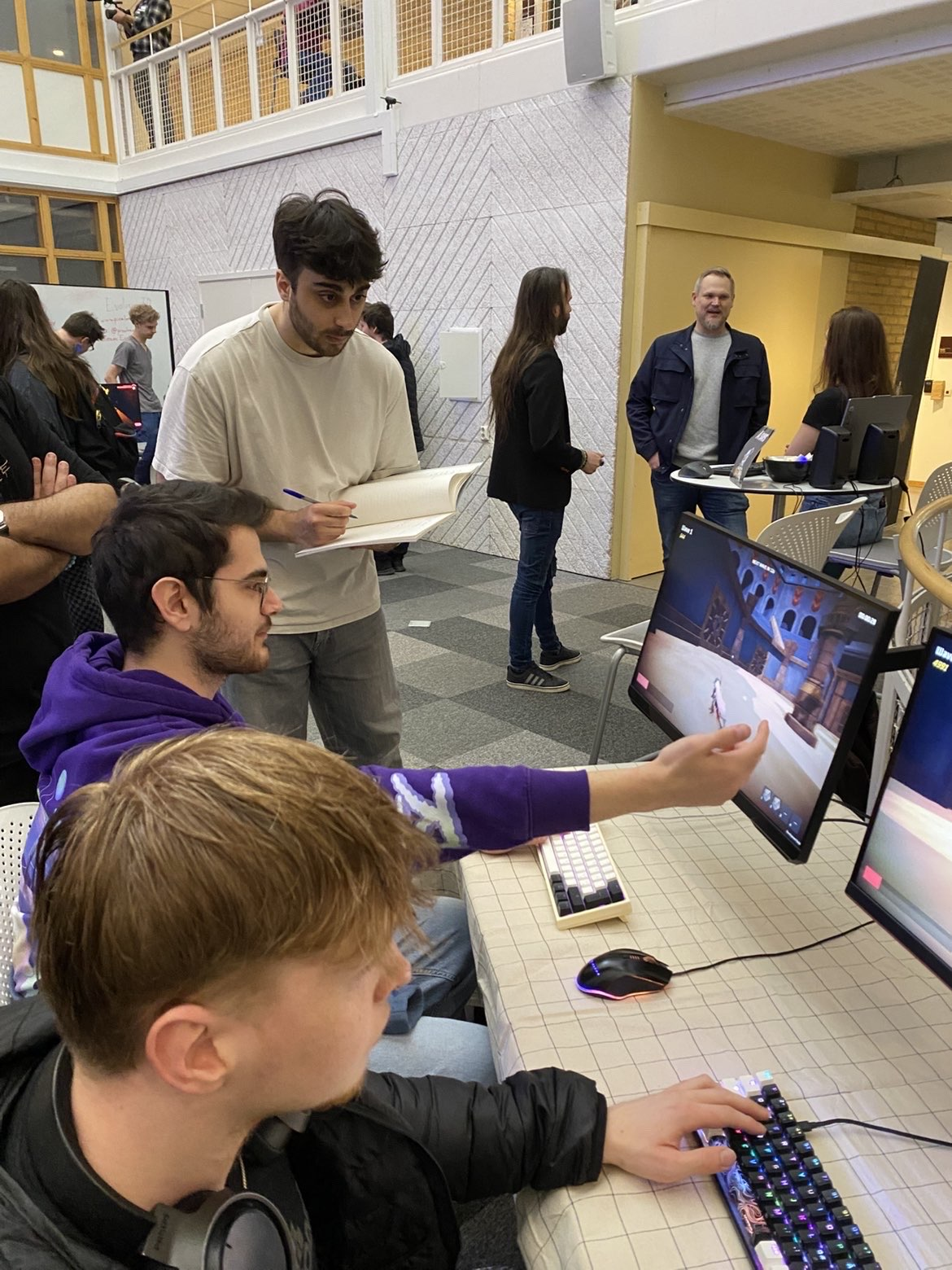 A player discussing Atira at the demo table while a team member takes notes